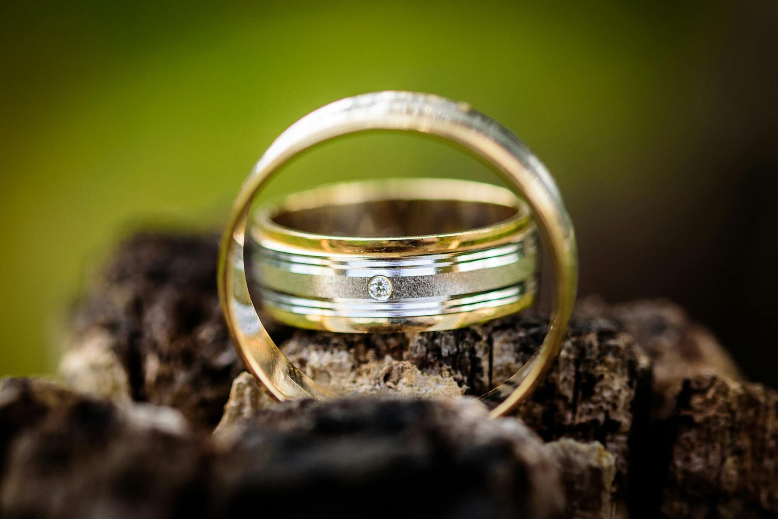 Rustic close-up of vintage gold wedding rings with diamond on wooden background.
